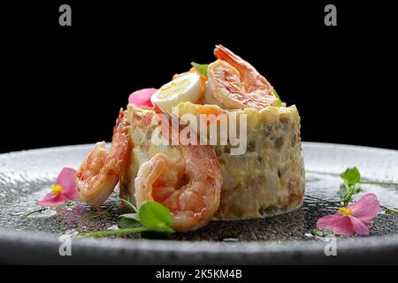 Olivier-Salat mit Garnelen und Lachs auf einem Teller Stockfoto