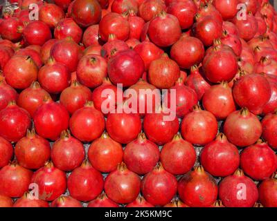 Haufen Granatapfel. Haufen von reifen ganzen Granatäpfeln, bereit, auf dem Obstmarkt zu verkaufen. Stockfoto