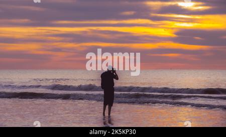 Silhouette eines Mannes, der bei Sonnenuntergang in Den Haag fotografiert Oder die Stadt Den Haag in den Niederlanden Stockfoto