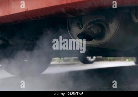 Rauch kommt aus dem Auspuffrohr eines alten Autos. Nahaufnahme. Das Konzept von Ökologie und Transport. Stockfoto