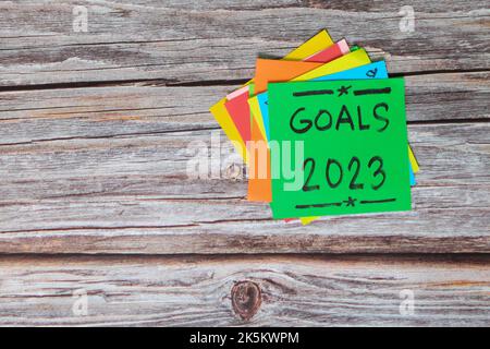 Ziele, Resolutionen und Konzept für das neue Jahr 2023. Bunte Haftnotizen auf Holzhintergrund. Stockfoto