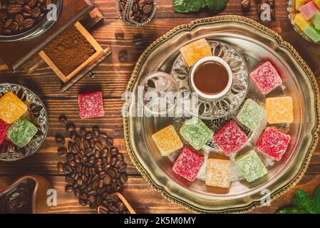 Türkische Kaffeetasse mit gerösteten Kaffeebohnen und türkischen Köstlichkeiten auf rustikalem Holzhintergrund. Draufsicht mit Kopierbereich. Stockfoto