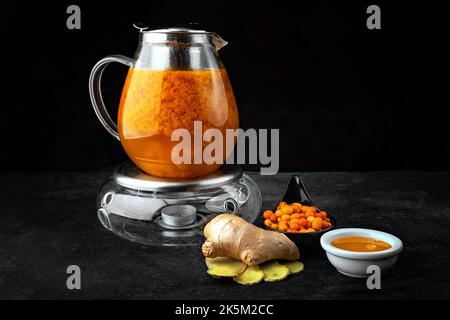 Tee mit Sanddorn und Ingwer in einer Glas-Teekane Stockfoto