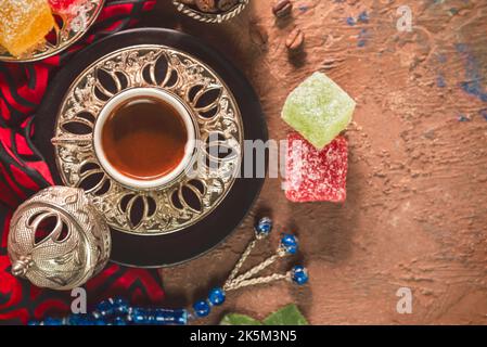 Türkische Kaffeetasse mit gerösteten Kaffeebohnen, türkischen Köstlichkeiten und Rosenkranz auf rustikalem Hintergrund. Draufsicht mit Kopierbereich. Stockfoto