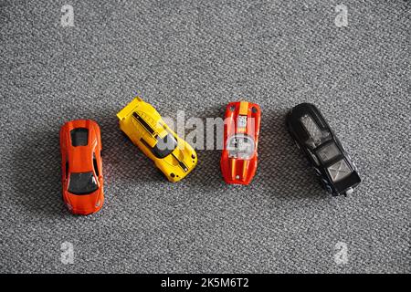 Eine Gruppe mehrfarbiger Spielzeugautos auf einer grauen, rauen Oberfläche Stockfoto