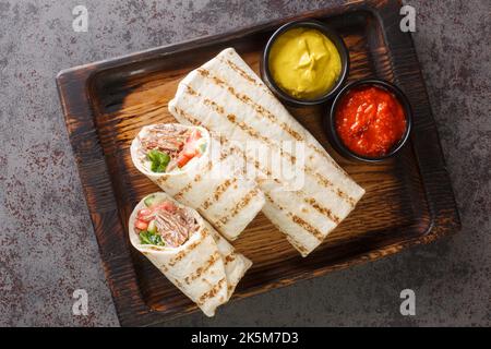 Shawarma Sandwich Gyro frische Rolle Lavasch Nahaufnahme auf dem Holzbrett auf dem Tisch. Horizontale Draufsicht von oben Stockfoto