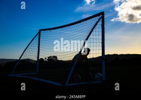 Jungen spielen Fußball, wenn das Licht versagt und der Abend fällt. Stockfoto