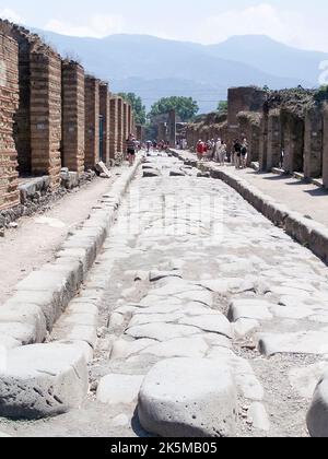 Gepflasterte Straße und Fußweg, mit Trittsteinen, um die Straße zu überqueren, um Exkremente und Wasser zu vermeiden, in einer Straße in Pompeji, Italien Stockfoto