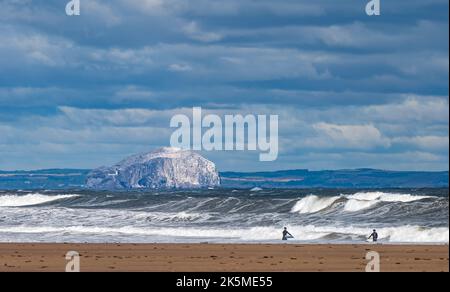 Surfer im Firth of Forth an einem windigen Tag mit großen Wellen mit der Bass Rock Insel in der Ferne, Schottland, Großbritannien Stockfoto