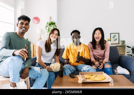 Multiethnische glückliche Freunde, die zu Hause Fernsehen Stockfoto