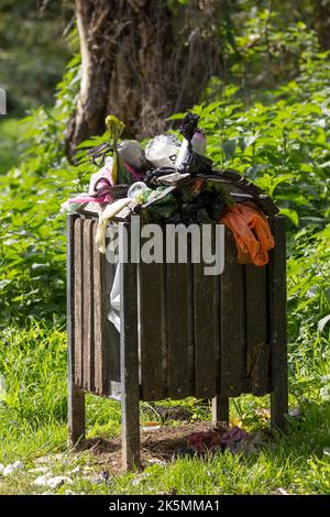 Mülltonne voll und überfüllt entlang des Flussufers. Voll von Lebensmittelverpackungen Getränkedosen und Flaschen Hund poo Taschen und verschiedene andere Abfälle im Porträt Stockfoto