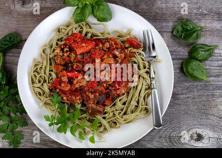Traditionelles klassisches italienisches Spaghetti-Gericht mit Pfeffer und Basilikumkräutern auf rustikalem Holztisch in flacher Laienansicht Stockfoto