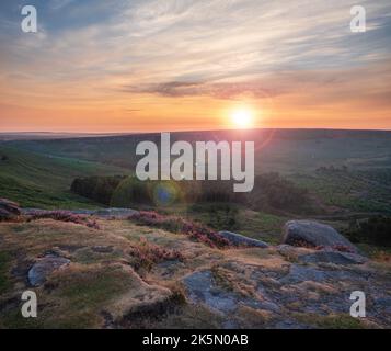 Atemberaubender spätsommerlicher Sonnenaufgang im Peak District über blühenden Heidefeldern rund um Higger Tor und Burbage Edge Stockfoto