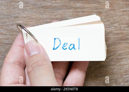 Hand halten Flash-Karte mit Handschrift in Wort Deal auf Holz Hintergrund Stockfoto