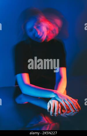 Psychische Störung. Angstattacke. Schizophrenie Psychiatrie. Doppelbelichtung Silhouette frustriert verrückt Frau schüttelt Kopf in rosa blau Neonfarbe Lig Stockfoto