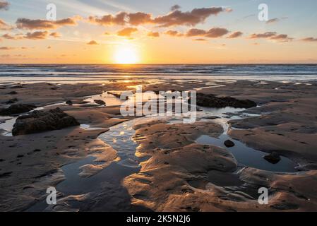 Schönes Landschaftsbild im Sommer bei Sonnenuntergang von Widemouth Bay in Devon England mit goldenem Stundenlicht am Strand Stockfoto