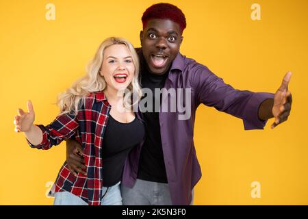 Glückliche Millennials. Multirassische Freundschaft. Tolle Gelegenheit. Sieg Freude. Überglücklich aufgeregt Freunde Mann Frau schrie isoliert auf orange Backgroun Stockfoto