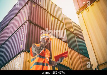 Arbeiter kommunizieren per Funk, um die Ladecontainer an der Hafenladung zu steuern Stockfoto