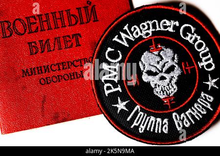 Ansicht eines Logos der russischen privaten Militärfirma 'Wagner Group' und eines russischen Militärausweises auf weißem Hintergrund Stockfoto