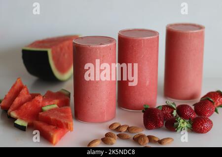 Erdbeer-Smoothie mit Wassermelone. Sommergetränk aus Wassermelone und frischen Erdbeeren in Mandelmilch. Aufgenommen auf weißem Hintergrund zusammen mit Wassermelone Stockfoto