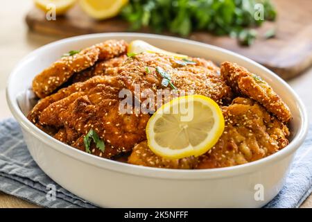 Saftiges und knuspriges paniertes Fleisch als Schnitzel werden mit einer Zitronenscheibe serviert. Stockfoto
