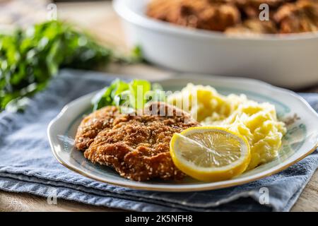 Paniertes Fleisch serviert mit Kartoffelbrei, Zitronenscheibe und Gemüse. Stockfoto