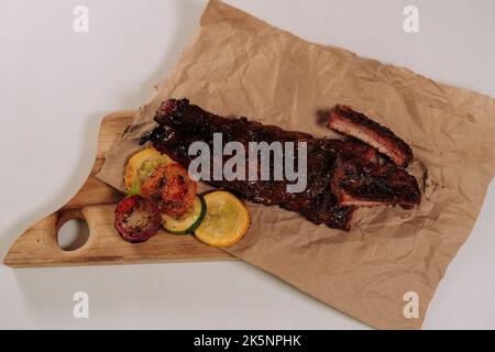Die Schweinerippchen mit gegrilltem Gemüse auf Holzbrett Stockfoto