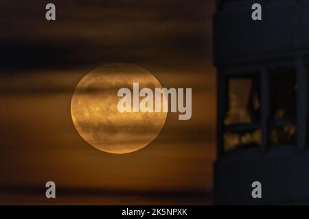 London, Großbritannien. 9.. Oktober 2022. Wetter in Großbritannien: Der volle Hunter's Moon steigt in der Nähe eines Hochhaus-Hochhauses im Südosten Londons. Nach Angaben der Almanac-Website geht man davon aus, dass die früheste Verwendung des Begriffs „Hunter’s Moon“ bis ins Jahr 1710 zurückreicht. Kredit: Guy Corbishley/Alamy Live Nachrichten Stockfoto