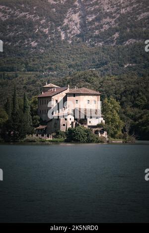 Eine vertikale Aufnahme eines alten Schlosses, umgeben von immergrünen Bergen mit einem See im Vordergrund Stockfoto
