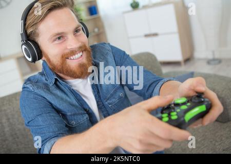 Mann, der einen Joystick-Controller hält, während er ein Videospiel spielt Stockfoto