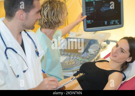 Arzt nimmt Notizen von einer Frau mit Ultraschall Stockfoto