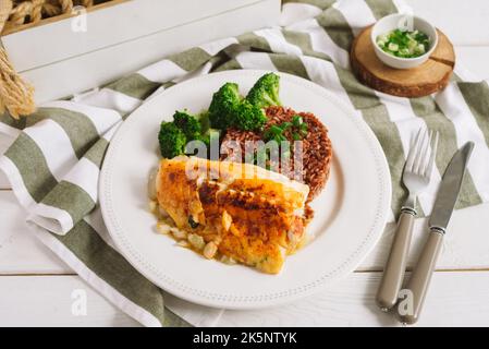 Kabeljaufilet mit braunem Reis und gedämpftem Brokkoli. Ein schönes Display auf dem Teller. Stockfoto