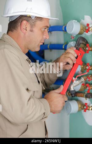 Reifer Klempner mit Schraubenschlüssel am Rohr Stockfoto