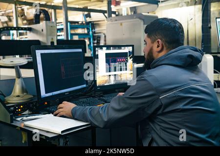 Perm, Russland - 21. September 2022: Der Bediener steuert die Industriemaschine, während er vor den Monitoren sitzt Stockfoto