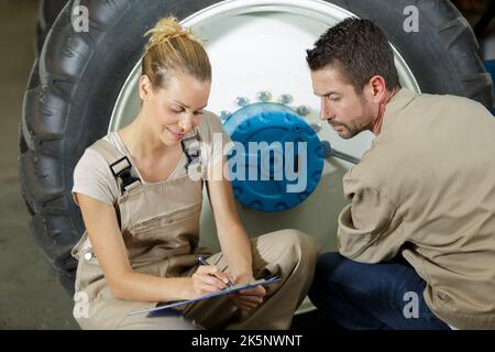 Glücklicher Mann und Frau, die mit Traktorrädern arbeiten Stockfoto