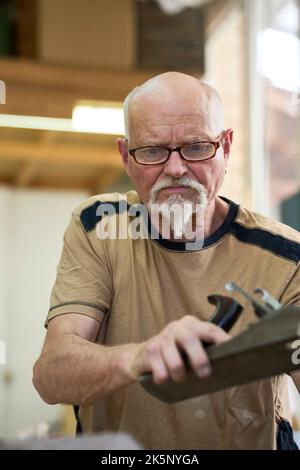 Antike Zimmerer arbeitet Holz mit Einem Flugzeug. Russikon, Schweiz Stockfoto