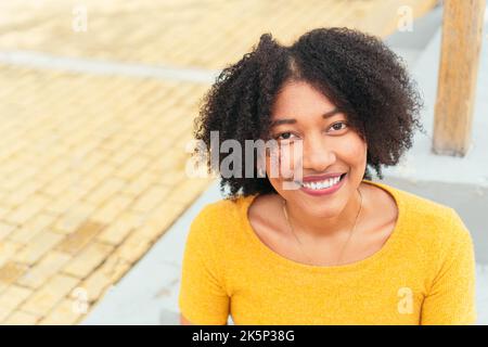 Junge Latina-Hündin mit afro, der die Kamera anschaut Stockfoto
