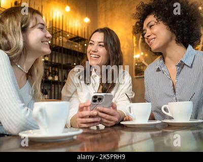 Drei Freunde in einem Café unterhalten sich glücklich miteinander Stockfoto