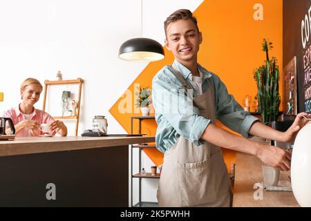 Ein hübscher Barista, der Kaffee für Besucher im Café zubereitet Stockfoto