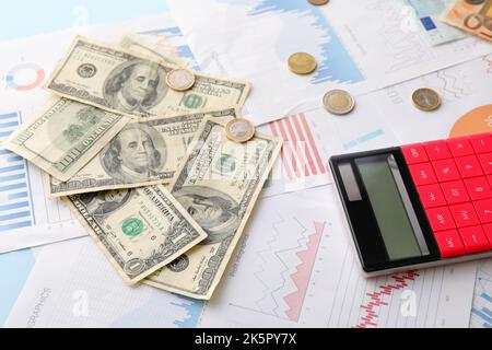 Dollar-Banknoten mit Münzen, Taschenrechner und Diagrammen auf blauem Hintergrund. Wechselkurskonzept Stockfoto