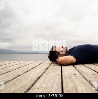 Junger Mann, der mit geschlossenen Augen in der Natur liegt. Konzept der Entspannung in der Natur Stockfoto