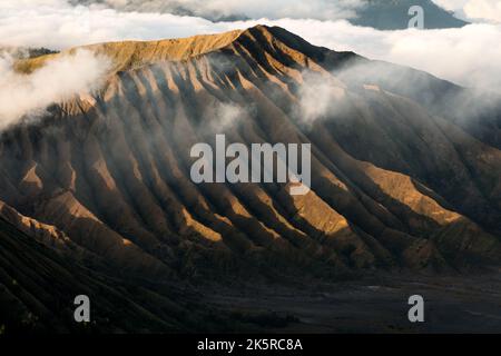 Mount Bromo, Berg im Tengger Semeru Nationalpark, Java bei Sonnenaufgang mit Meereswolken, die schwarze Schatten bilden, Indonesien Stockfoto