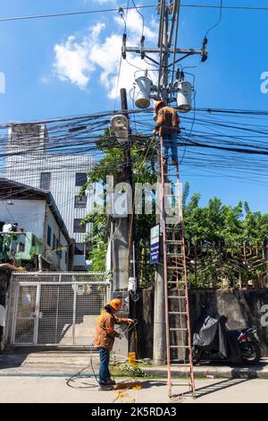 Linienarbeiter eines Energieunternehmens, das an einem Strommast in Cebu City, Philippinen, arbeitet Stockfoto