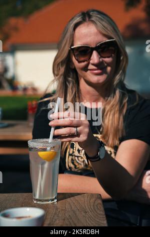 Porträt der reifen Frau, die im Restaurant sitzt und Limonade trinkt Stockfoto