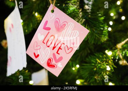 Ich liebe Sie Postkarte auf dem Weihnachtsbaum. Postkarten und Laternen auf dem Weihnachtsbaum für den Feiertag.Botschaft des neuen Jahres Stockfoto