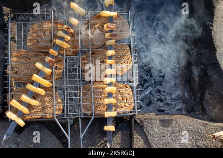 Nahaufnahme der am Lagerfeuer gerösteten Schweineldstücke. Draufsicht. Barbecue auf Feuer. Erholung in der Natur, Aktivitäten in der wilden Umgebung Stockfoto