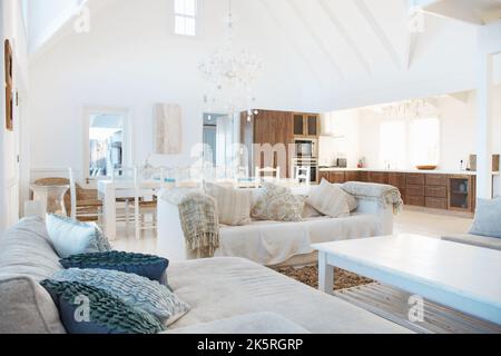 Entspannender, moderner Lebensstil. Modernes, geräumiges Wohnzimmer mit Esstisch und Küche im Hintergrund. Stockfoto