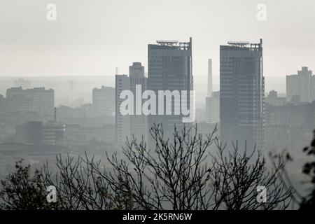 Skyline der Stadt. Hochhäuser, die am frühen Morgen aus dem Nebel aufsteigen. Selektiver Fokus auf Gebäude. Stockfoto