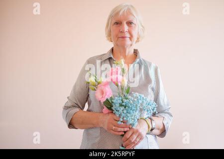 Gealterte Frau mit Blumenstrauß. Stockfoto