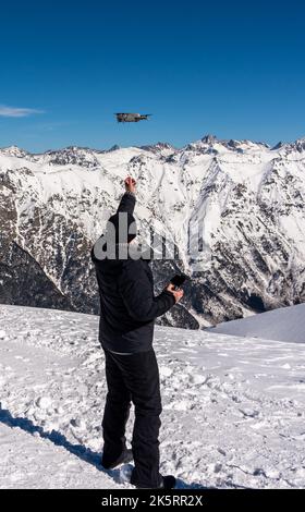 Drohne, die im Winter von der männlichen Hand auf dem Gipfel des verschneiten Berges abheben Stockfoto